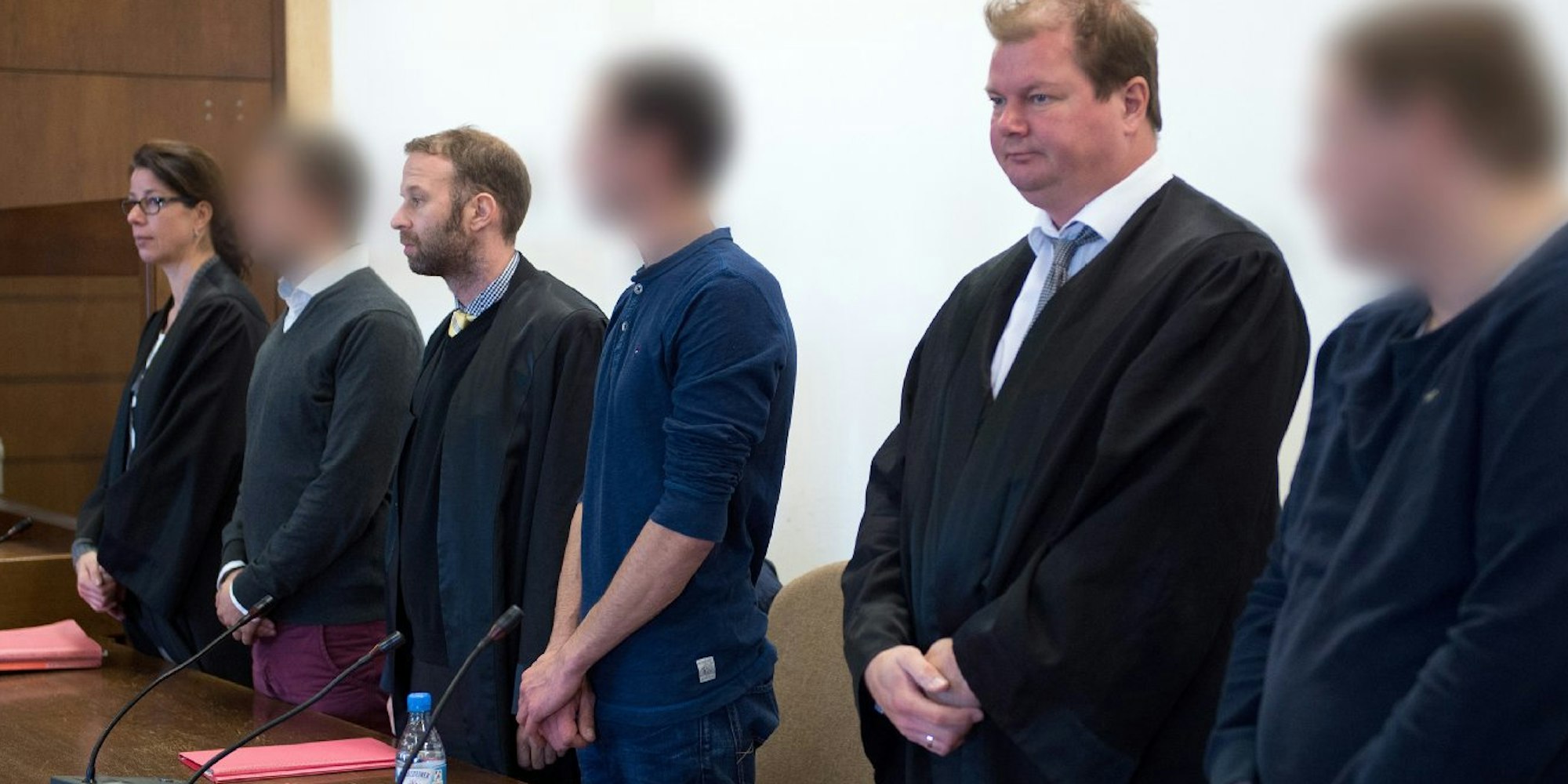 Die drei angeklagten Fußballfans stehen im Landgericht Köln - zwischen ihren Anwälten Alexandra Stolley (v.l.), Tobias Nikolas Westkamp und Jan-Henrik Heinz.