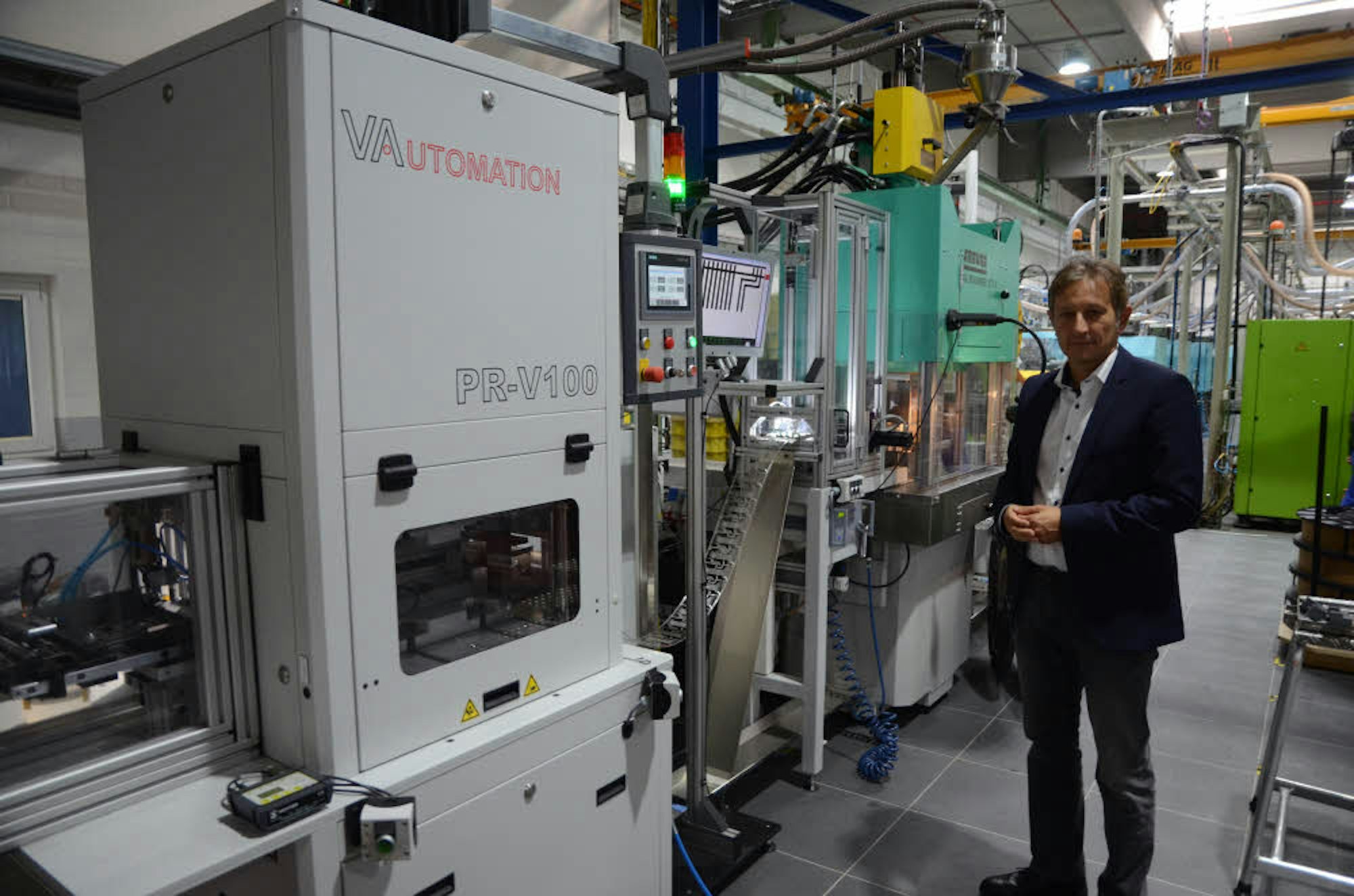 Geschäftsführer Selahattin Servi an einer der automatisch arbeitenden Maschinen im Bereich Spritzguss. Hier werden gestanzte Artikel mit Kunststoff umspritzt.