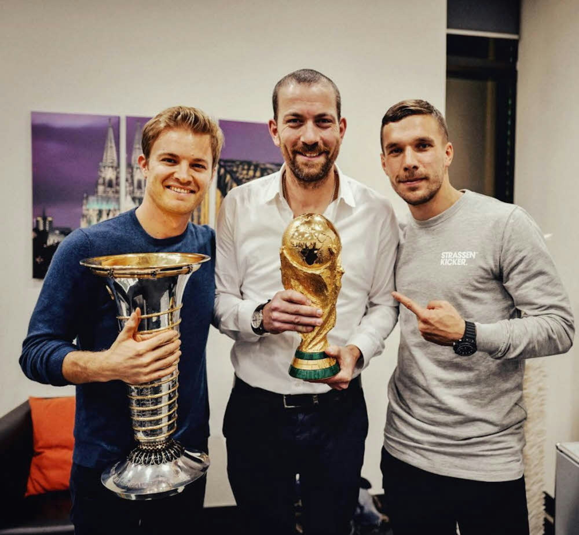 Rosberg, Nolte und Podolski mit WM-Pokalen.