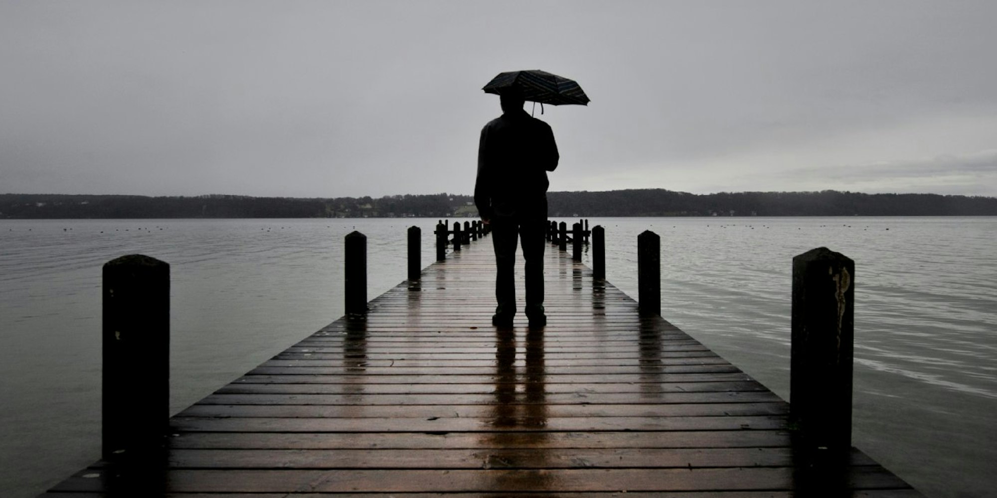 Ein Mann steht auf dein Steg am See.