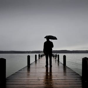 Ein Mann steht auf dein Steg am See.