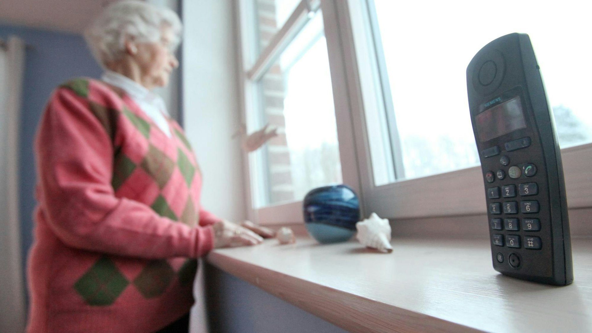 Eine Rentnerin schaut aus dem Fenster.