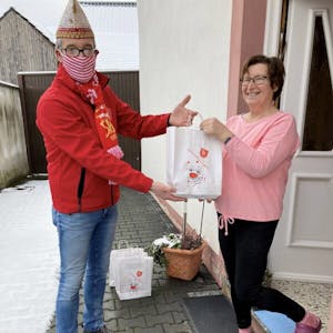 Karneval in d’r Täsch: BKV-Präsident Jürgen Hoscheid überreicht die jecke Papiertüte an eine Bürvenicherin.
