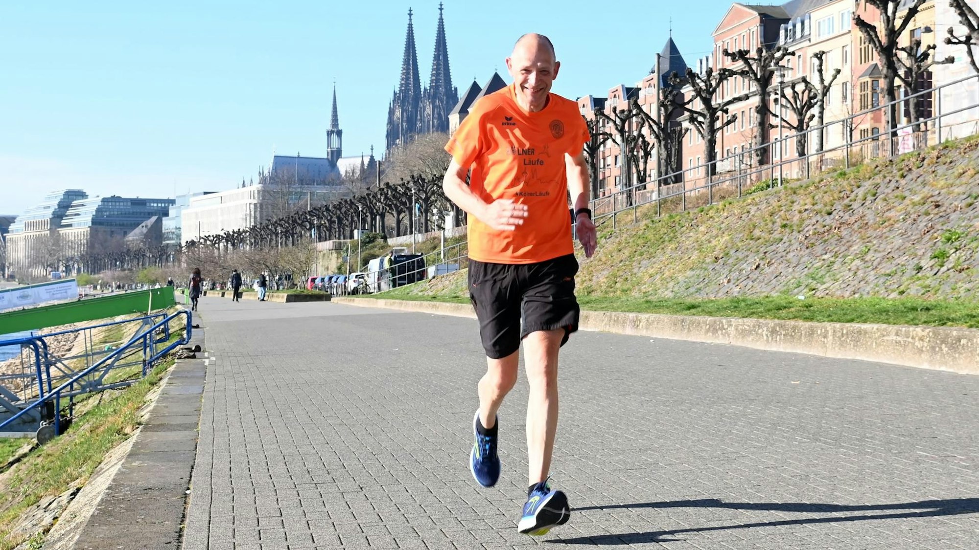 Mann joggt am Rheinufer, Kölner Dom im Hintergrund