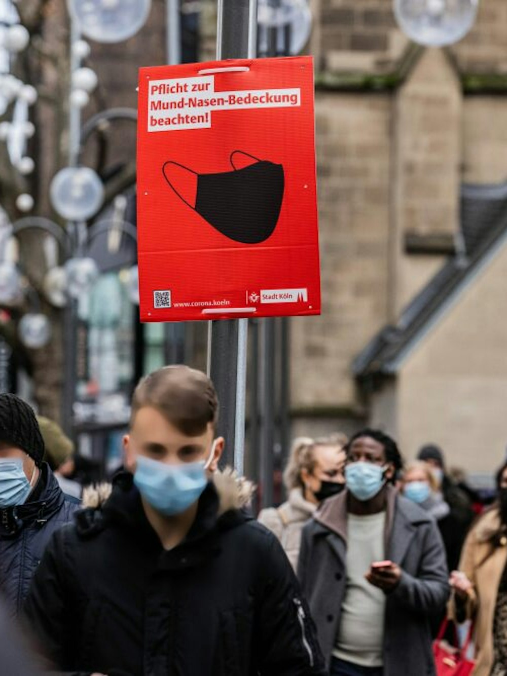 Auf den Einkaufsstraßen weisen rote Plakate auf die Maskenpflicht hin. 