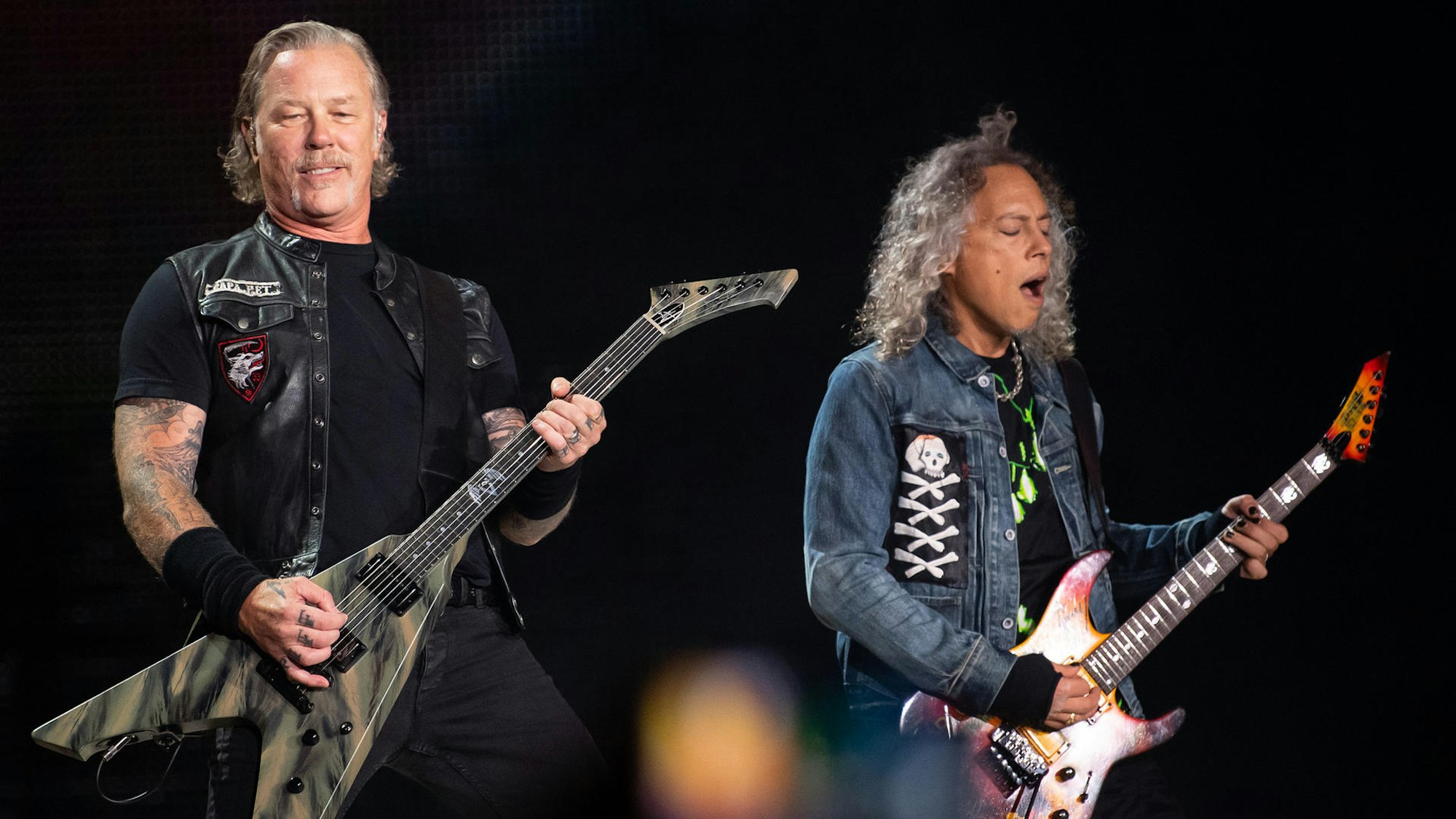 James Hetfield und Kirk Hammett von Metallica stehen auf der Bühne und spielen E-Gitarre.