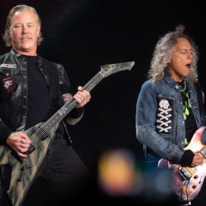 Zwei Bandmitglieder von Metallicas stehen auf der Bühne und spielen E-Gitarre.