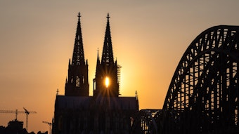 Der Kölner Dom mit Sonne, die durch die beiden Kirchtürme scheint