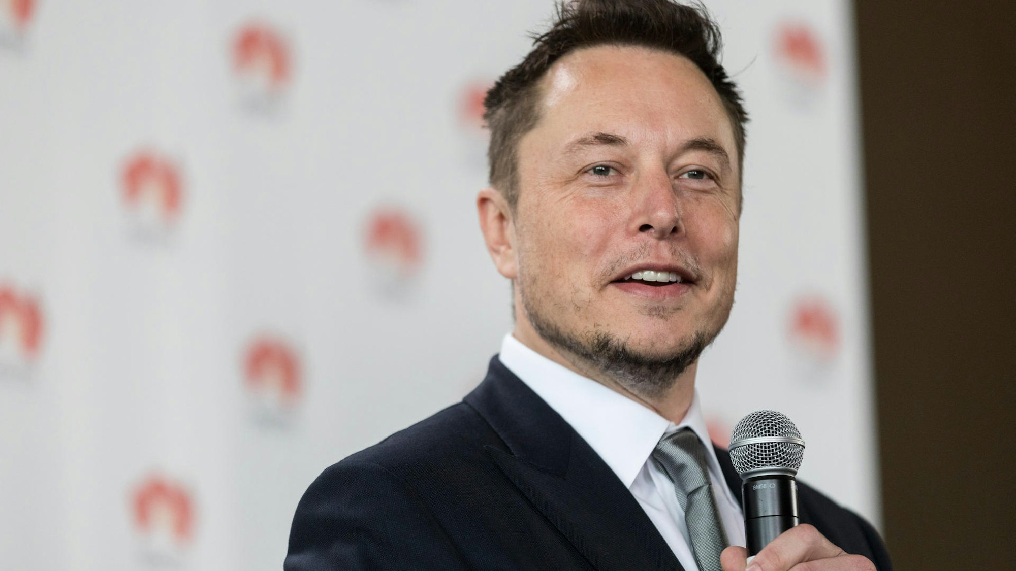 Elon Musk spricht in ein Mikrofon.