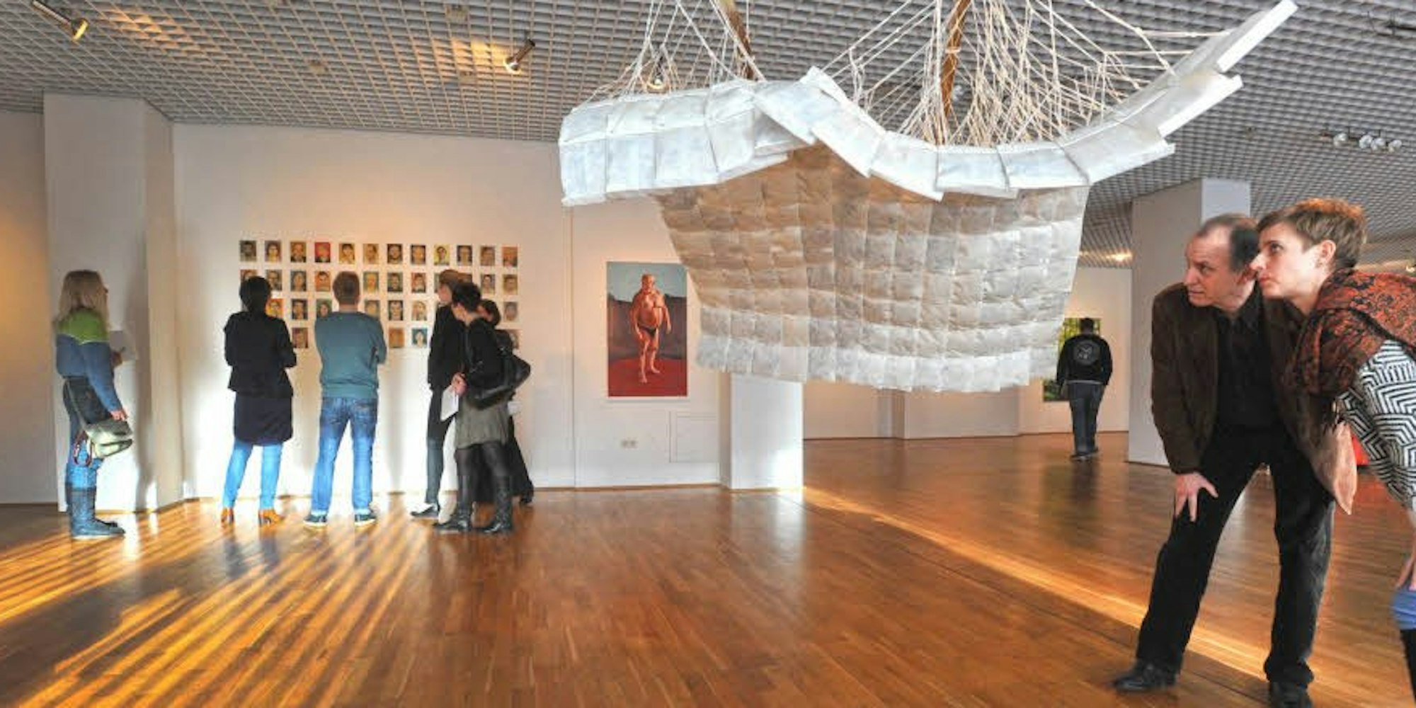 Kunst an der Wand und im Raum: Eileen Dreher (r.) begutachtet mit Peter Bömmels ihr an der Decke hängendes „Sonnendeck“.
