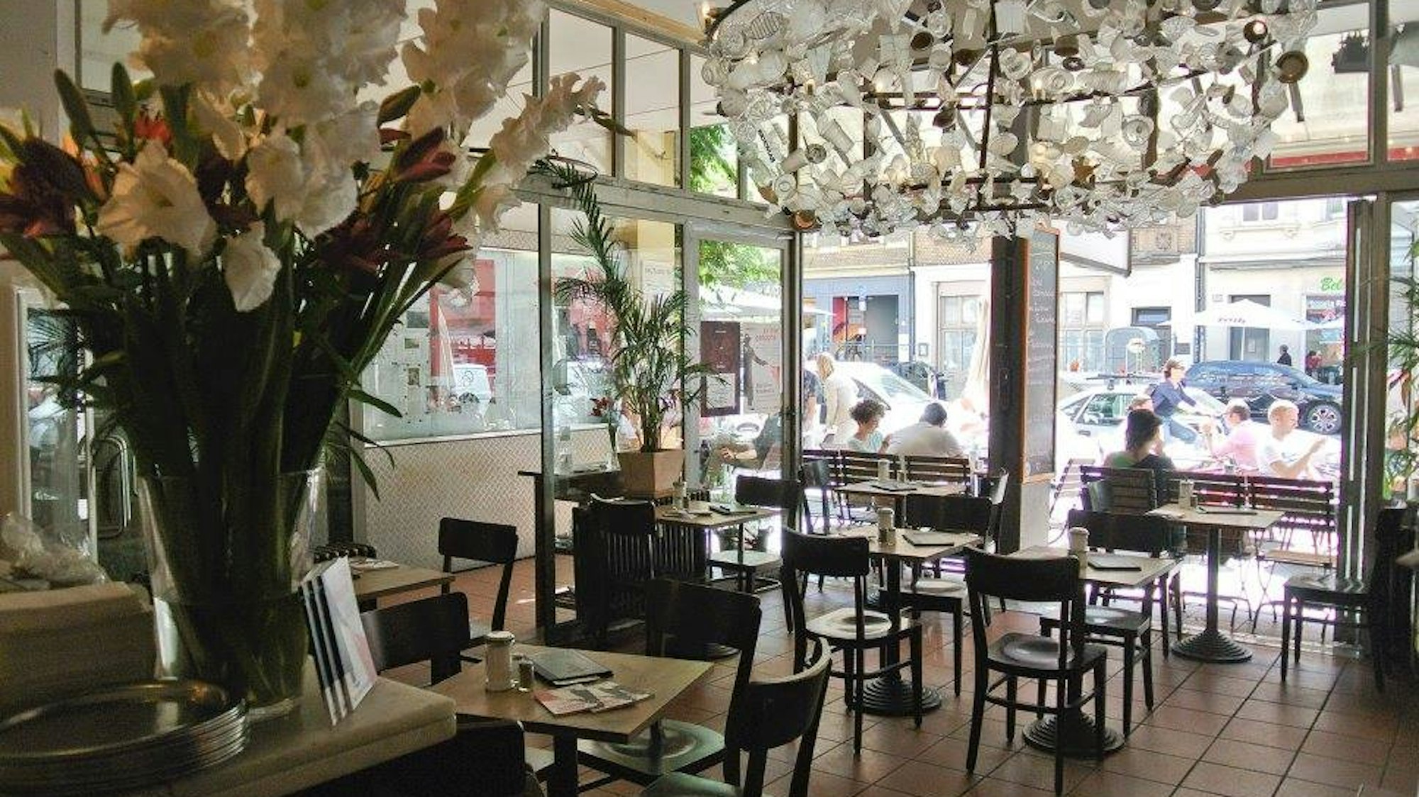 Das Café Bauturm von innen, ein großer Blumenstrauß steht im Vordergrund und an der Decke hängt ein großer Kronleuchter