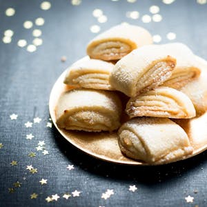 Zuckrige Marzipanballen liegen auf einem Teller angerichtet, rundherum sind goldene Sternchen verteilt