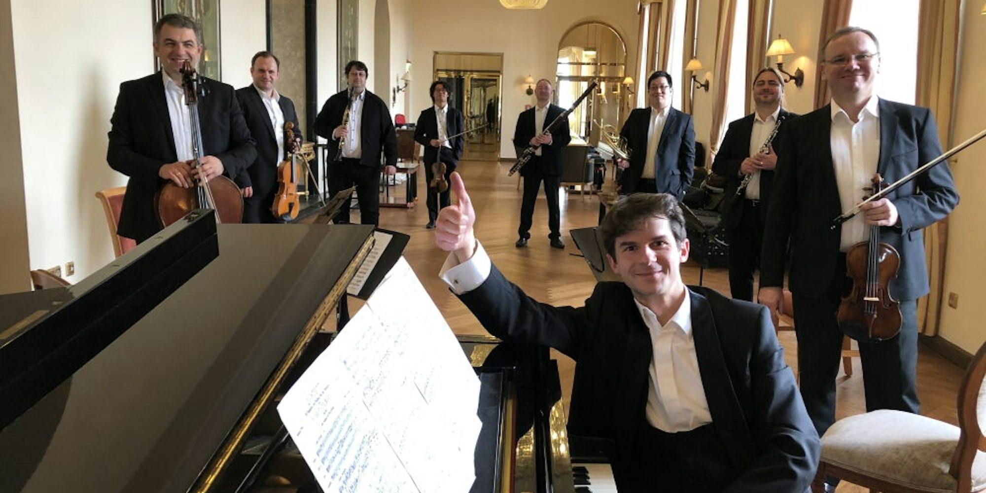 Neun Streicher und Bläser musizieren zusammen unter Leitung des Pianisten Roman Salyutov.