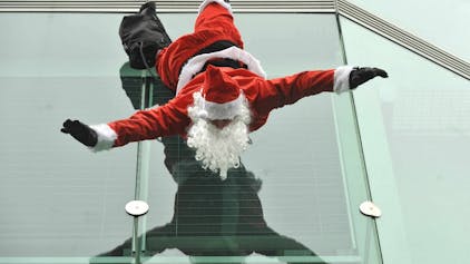 Ein Weihnachtsmann hängt kopfüber an einem Gebäude.