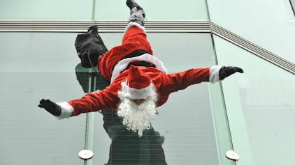 Ein Weihnachtsmann hängt kopfüber an einem Gebäude.