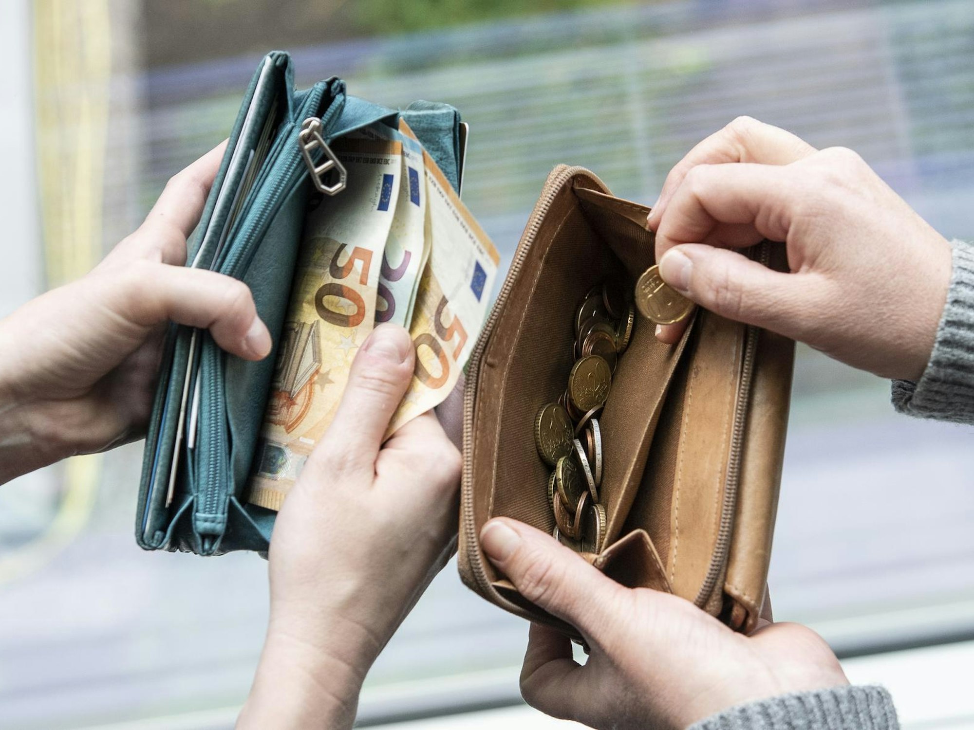 Menschen zeigen Geld in ihren Portemonnaies. Dieses wird durch eine Reform weniger.