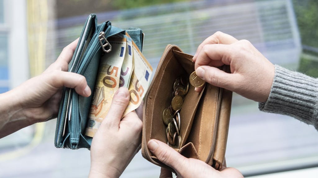 Menschen zeigen Geld in ihren Portemonnaies. Dieses wird durch eine Reform weniger.