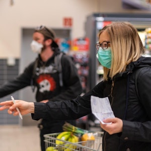 Kunden gehen in einem Supermarkt einkaufen und tragen dabei Mundschutz