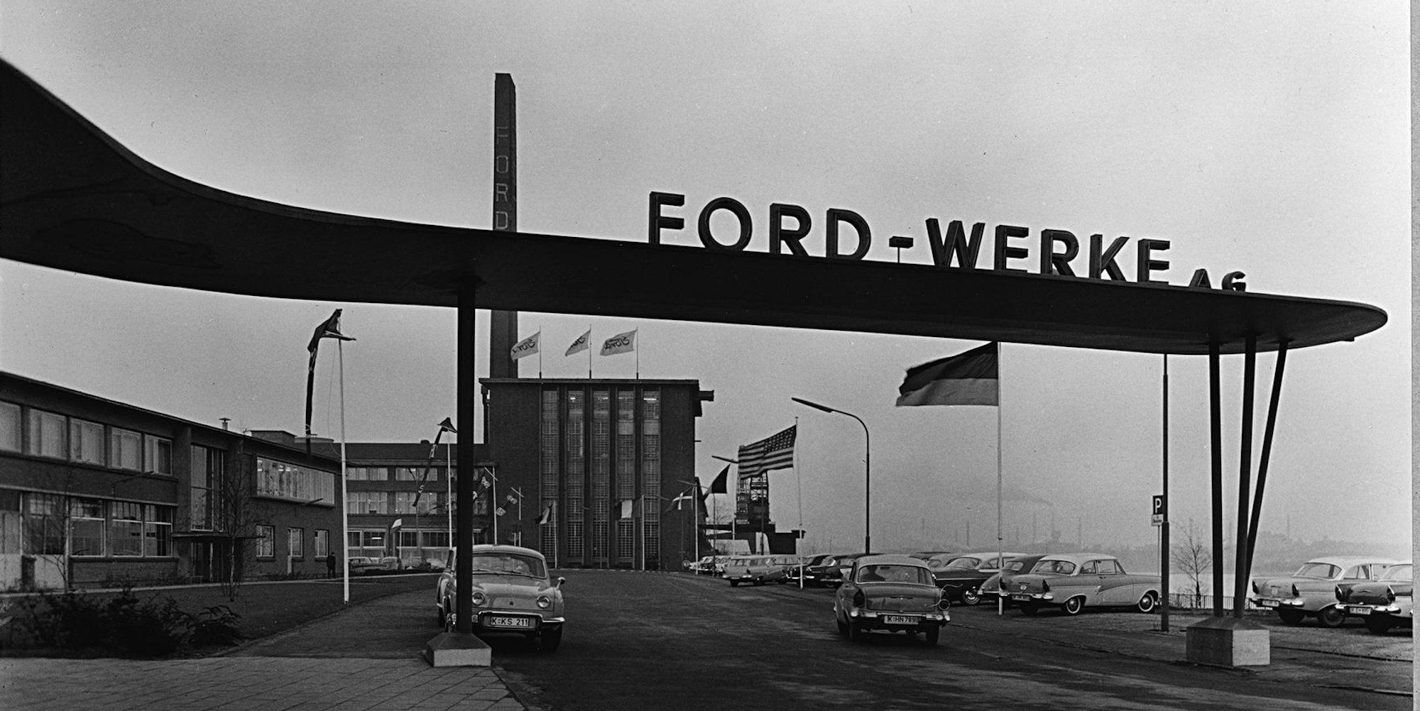 In den ausgehenden 1950er Jahren schmückte ein filigranes Dach den Eingangsbereich der Ford-Werke direkt am Rheinufer. Das gibt es heute nicht mehr, dafür verhindert die Hochwasserschutzmauer, dass die Straße bei Hochwasser gesperrt werden muss. 