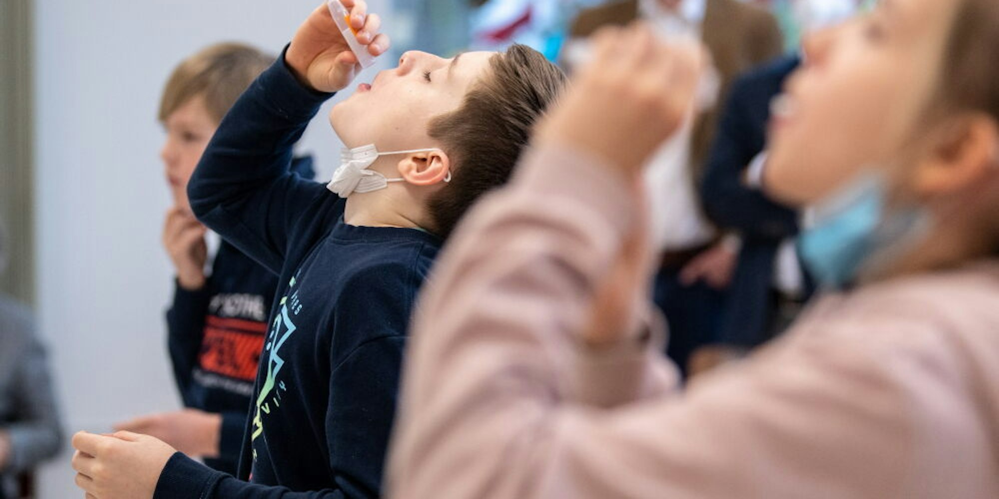 Während des Unterrichts lassen sich Schüler zwecks Coronatest ein Watteröhrchen in den Mund fallen, das den Speichel aufsaugt. Selbsttests in den Schulen sollen ab nächster Woche in NRW möglich sein. (Symbolbild)