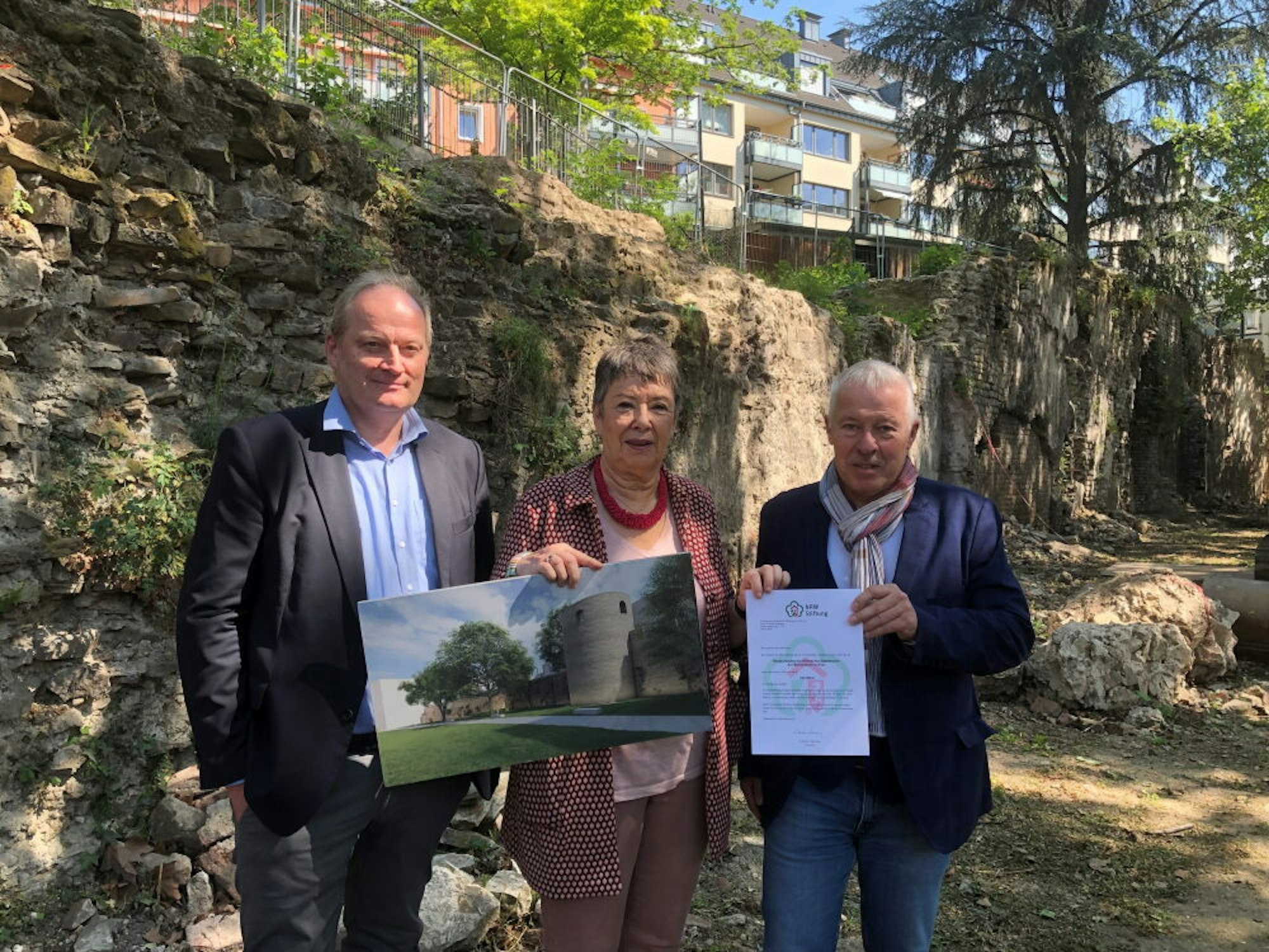 Karl-Heinz Erdmann von der NRW-Stiftung (r.) mit Barbara Schock-Werner und Marcus Trier (l.) vor der Römermauer.