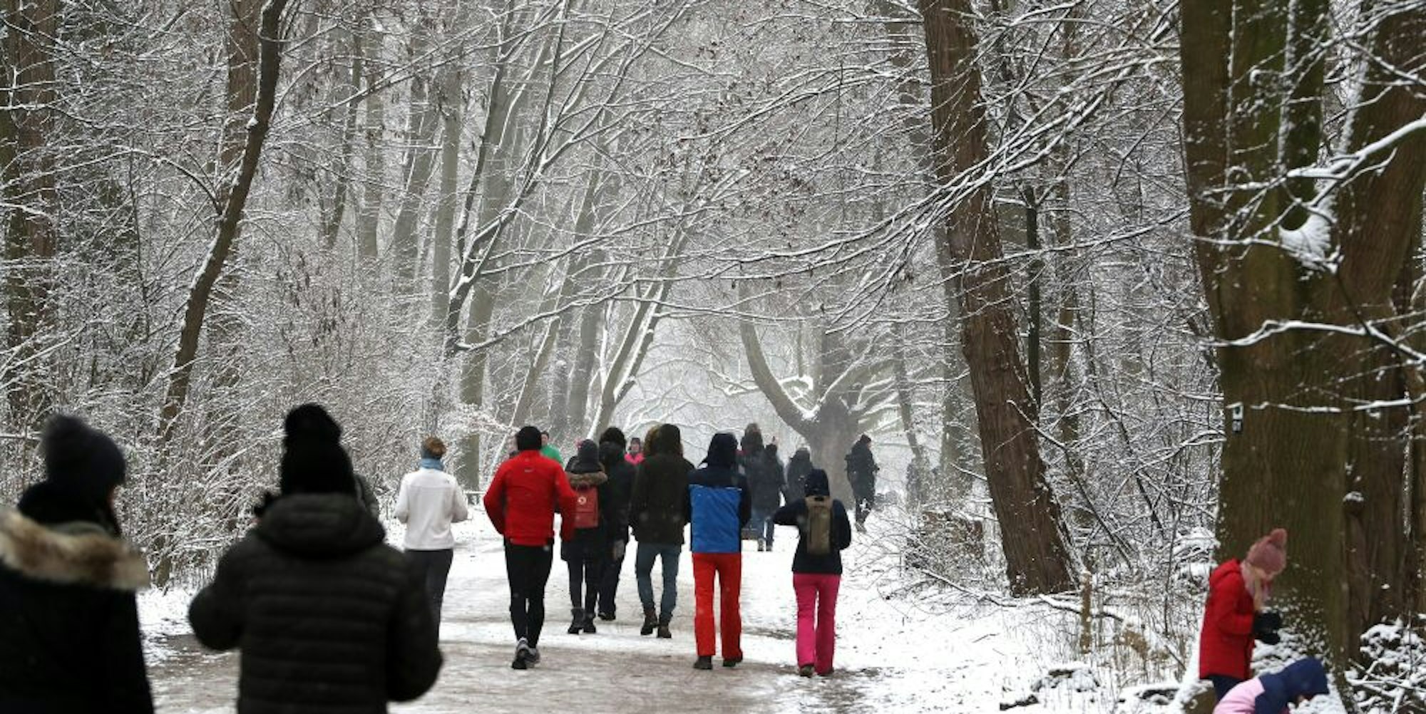 Spaziergänger im schneebedeckten Grüngürtel am Sonntag
