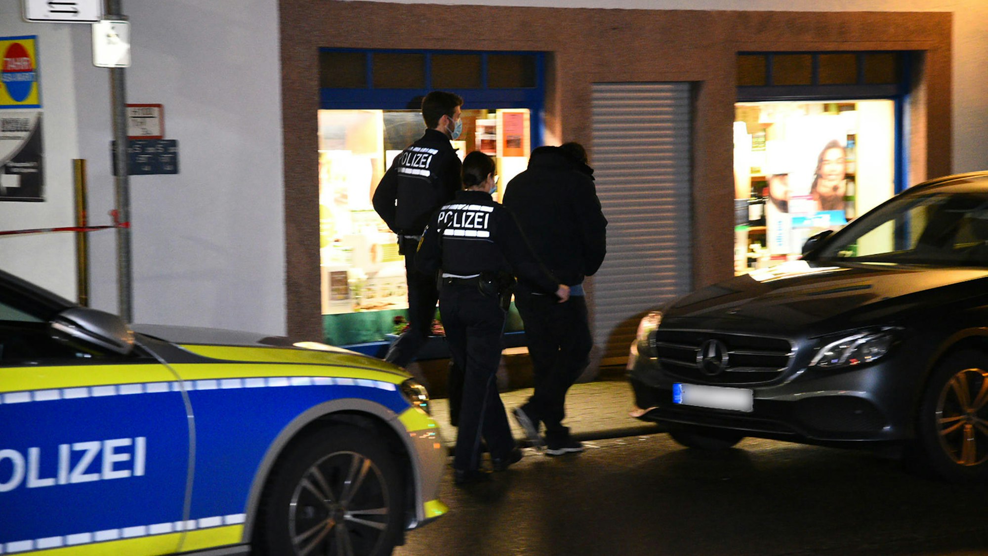 Zwei Polizisten kontrollieren einen jungen Mann.