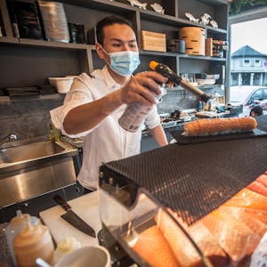 Nicht nur roher Fisch: Nino Wang flambiert den Lachs auf einer Sushirolle, Gäste können bei der Zubereitung zuschauen.