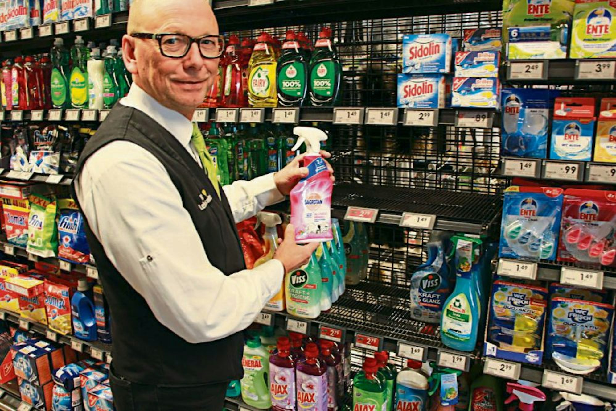 Das Fach ist leer: Die letzte Flasche Desinfektionsmittel hält Marktleiter Uwe Dönni von Edeka in Lohmar in seinen Händen.