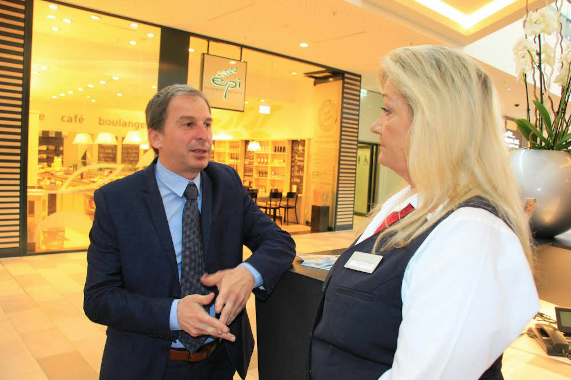 Huma-Manager Alexandros Papadopoulos im Gespräch mit einer Mitarbeiterin am Infostand im Einkaufscenter