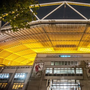 Blick von außerhalb des Stadion: Nachts reflektiert das Kunststoffdach das goldene Streulicht der Wachstumslampen auf dem Spielfeld.