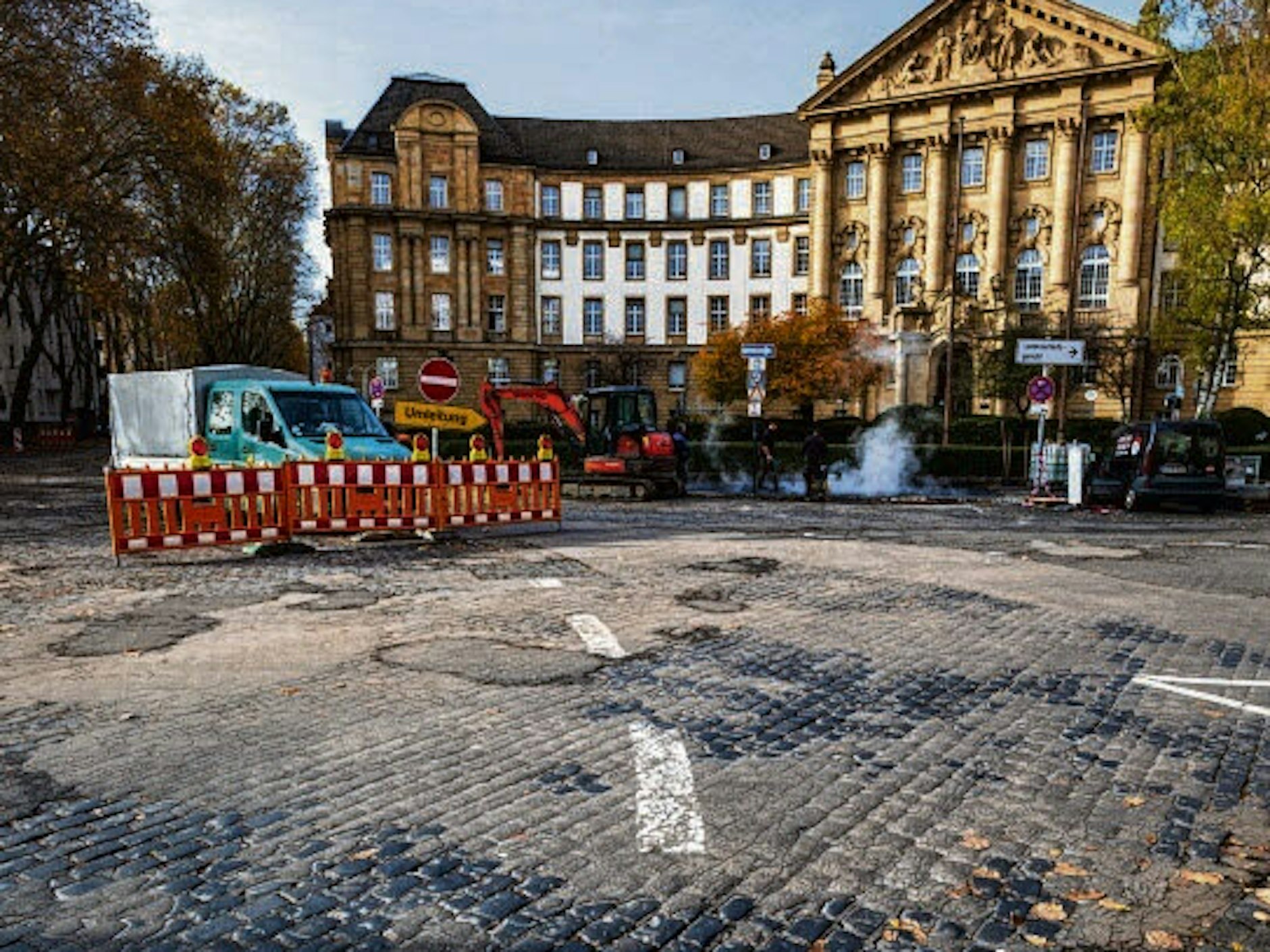 Die beiden mahnen seit Jahren die Straßenverhältnisse vor dem Oberlandesgericht an. Jetzt sind Arbeiter angerückt. Außerdem kritisieren sie den U-Bahn-Abgang Reichensperger Platz.