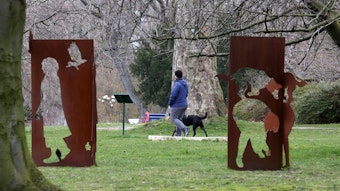 Skulpturen aus rostbraunem Metall auf einer grünen Wiese in einem Park