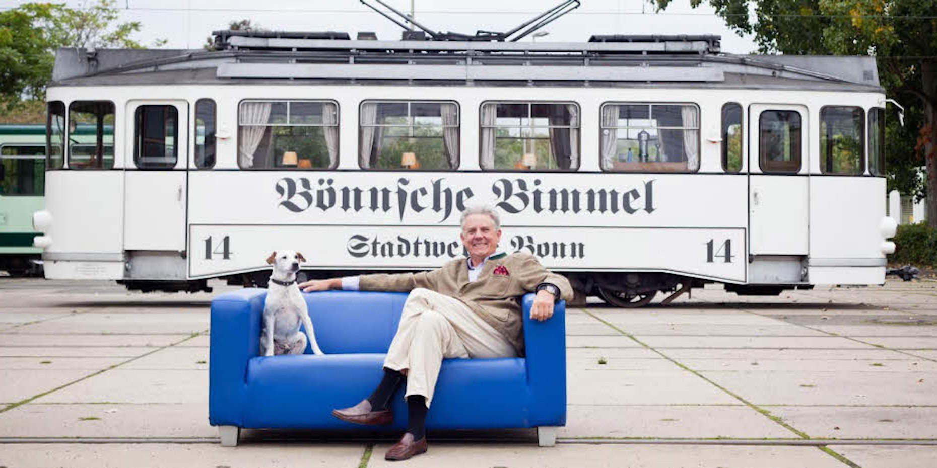 Hinter sich die Bönnsche Bimmel, neben sich Hund Milo: Bahnbetreiber Uli Hauschild auf der blauen Couch der Stadtwerke.