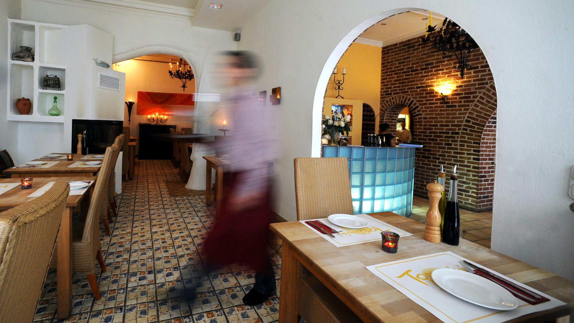 Das Restaurant Toscanini mit großem Bogen-Durchgang, italienischen Fliesenboden und Holztischen.