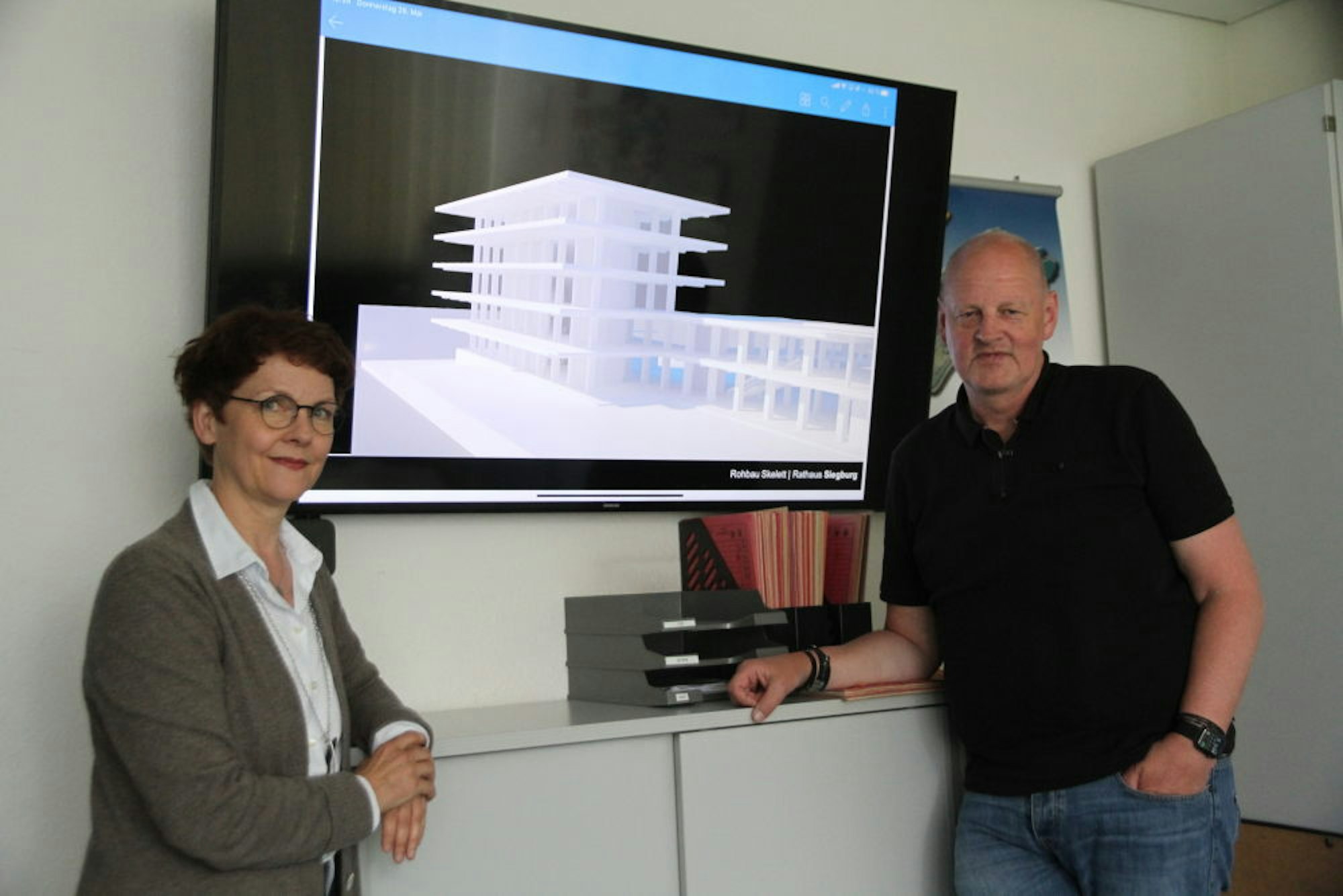 Barbara Guckelsberger und Bernd Lehmann vor einer Ansicht des für die Sanierung skelettierten Rathauses.