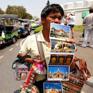 Ein Souvenirverkäufer wartet vor dem Großen Palast in Bangkok (Thailand) auf Touristen. Thailand bekommt das Dauerproblem Nepp nicht in den Griff.