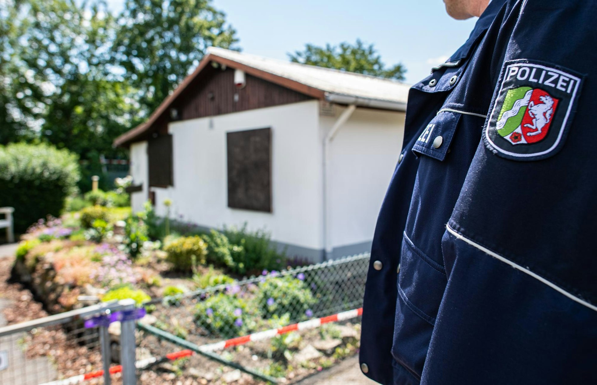 Ein Polizeibeamter vor der Gartenlaube, wo der vermutliche Haupttäter von Münster Teile seiner Server-Anlage unterbrachte.