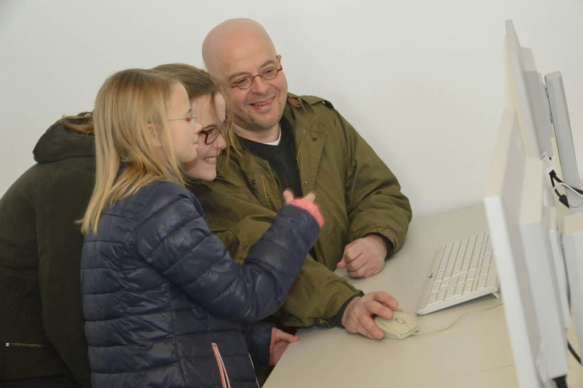 Kreisarchivar Manfred Huppertz sucht mit seinen Töchtern Dana und Norea auf dem Monitor nach alten digitalisierten Zeitungsartikeln.