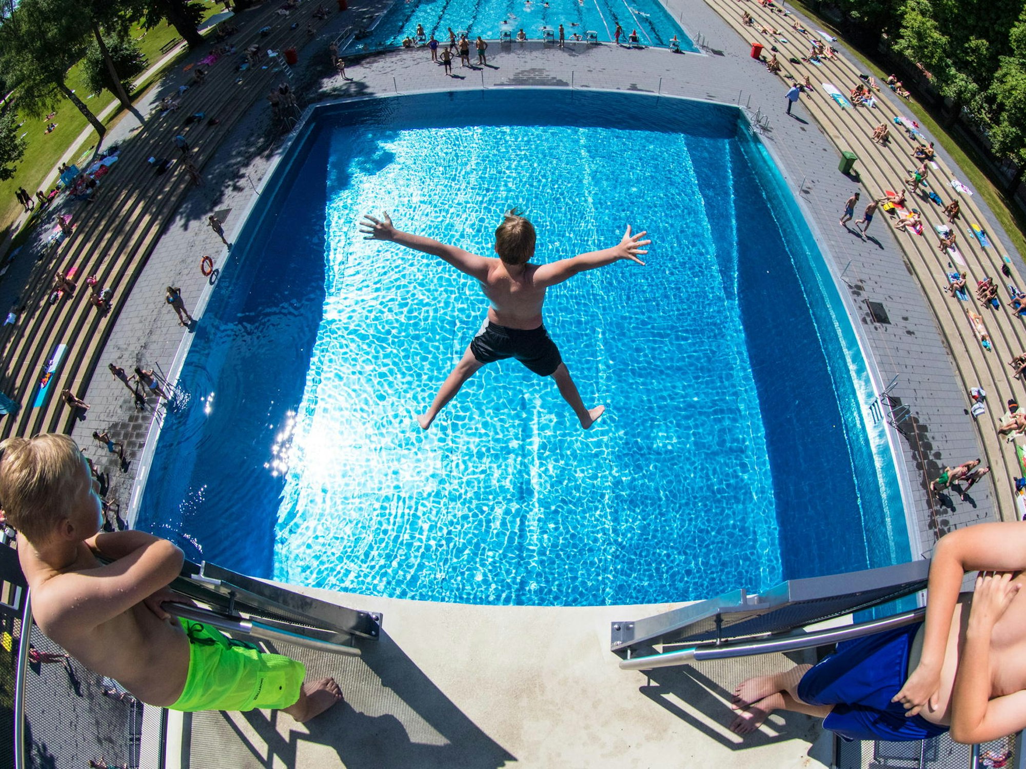 Ein Junge springt von einem Sprungbrett in ein Schwimmbecken.