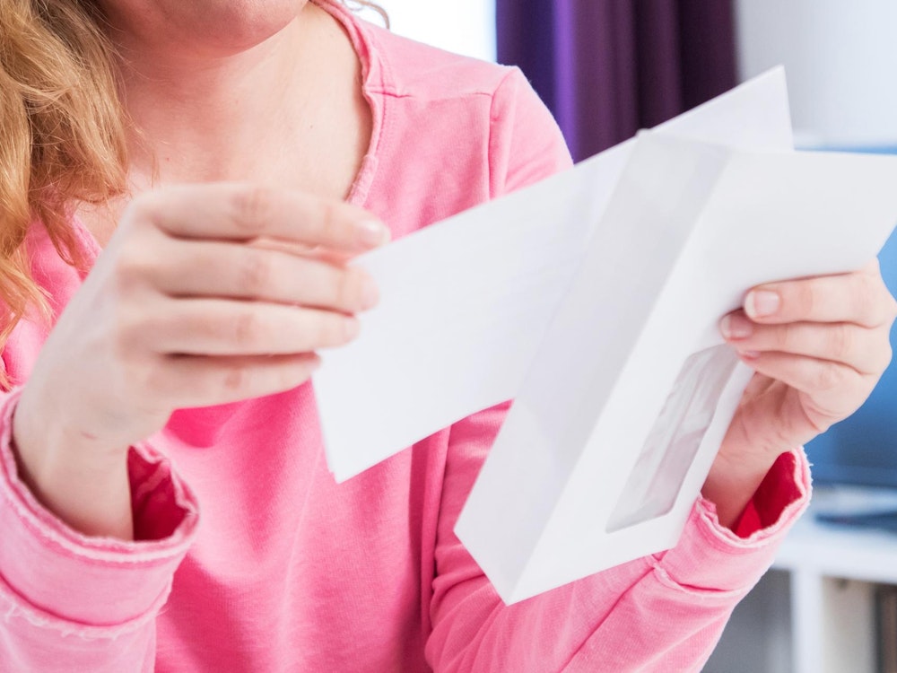 Eine Frau öffnet einen Briefumschlag.