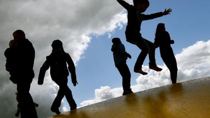 Kinder springen draußen auf einer Hüpfburg
