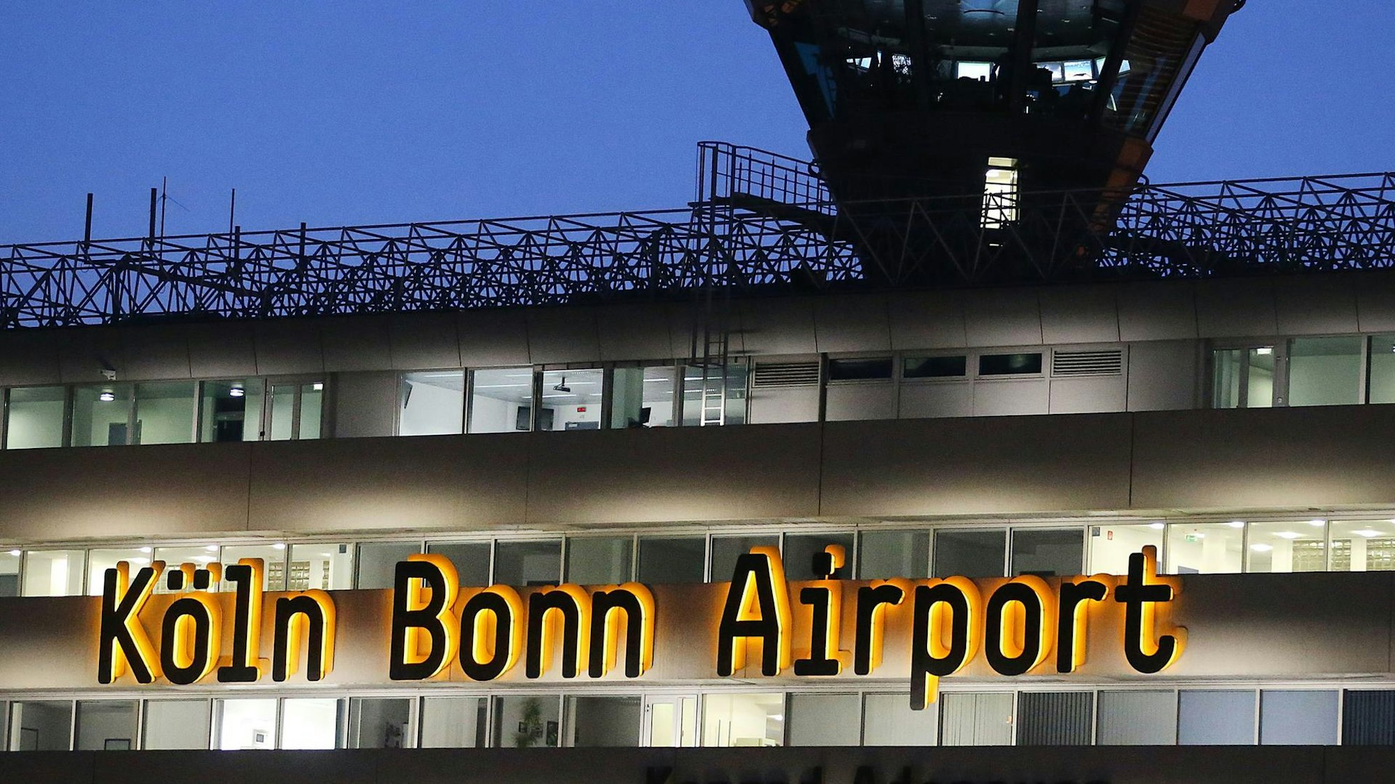 Der schwarz-gelbe Schriftzug "Köln Bonn Airport" an einem Flughafengebäude.