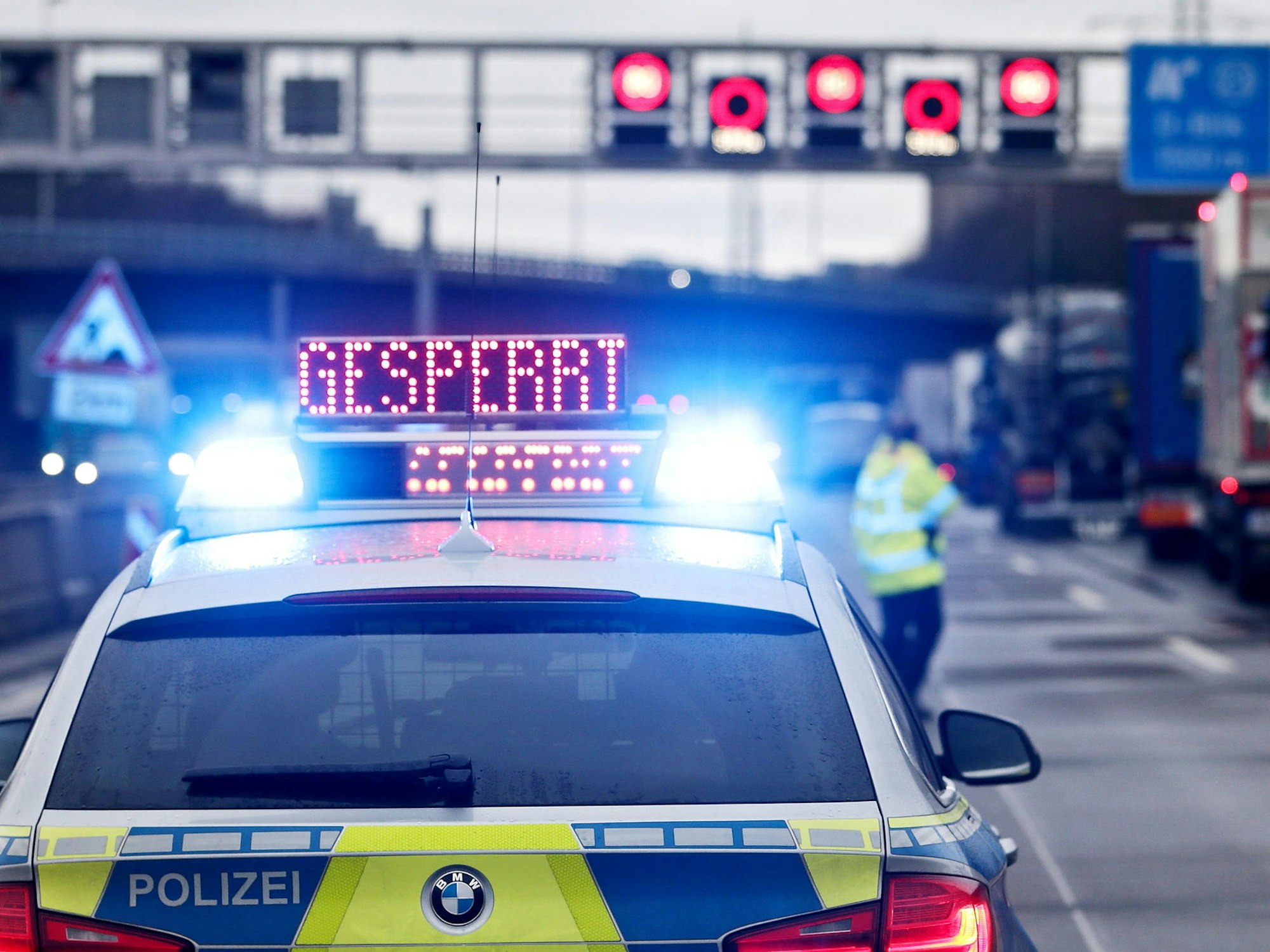 Ein Polizeiwagen steht auf der Autobahn, auf seinem Dach befindet sich ein Hinweisschild mit dem Wort „Gesperrt“.