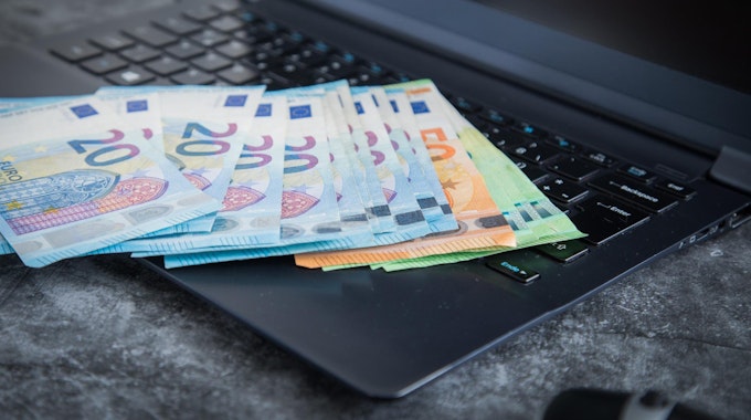 Verschiedene Euro-Scheine liegen auf einem Laptop.