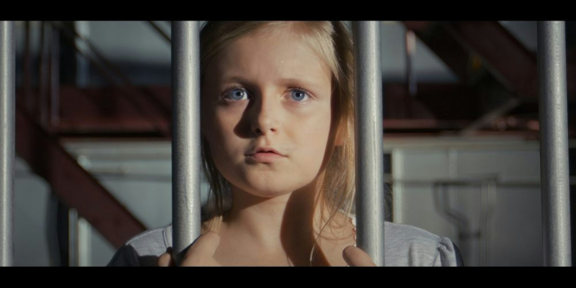 Die Kinderschauspielerin im neuen Kidkit-Video ist hinter Gitterstäben gefangen.