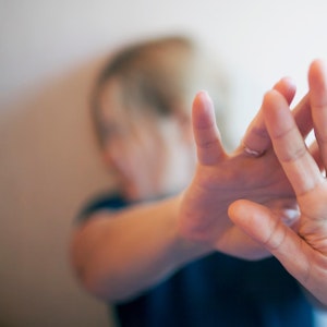 Eine Frau wehrt sich mit ihren Händen.