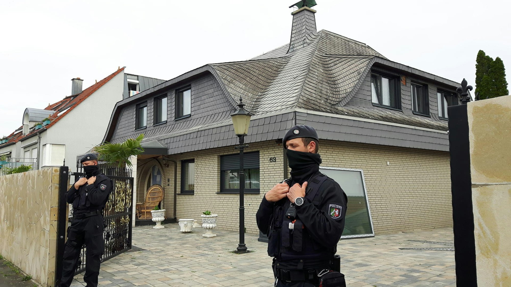 Ein maskierter Polizist steht vor einem Haus