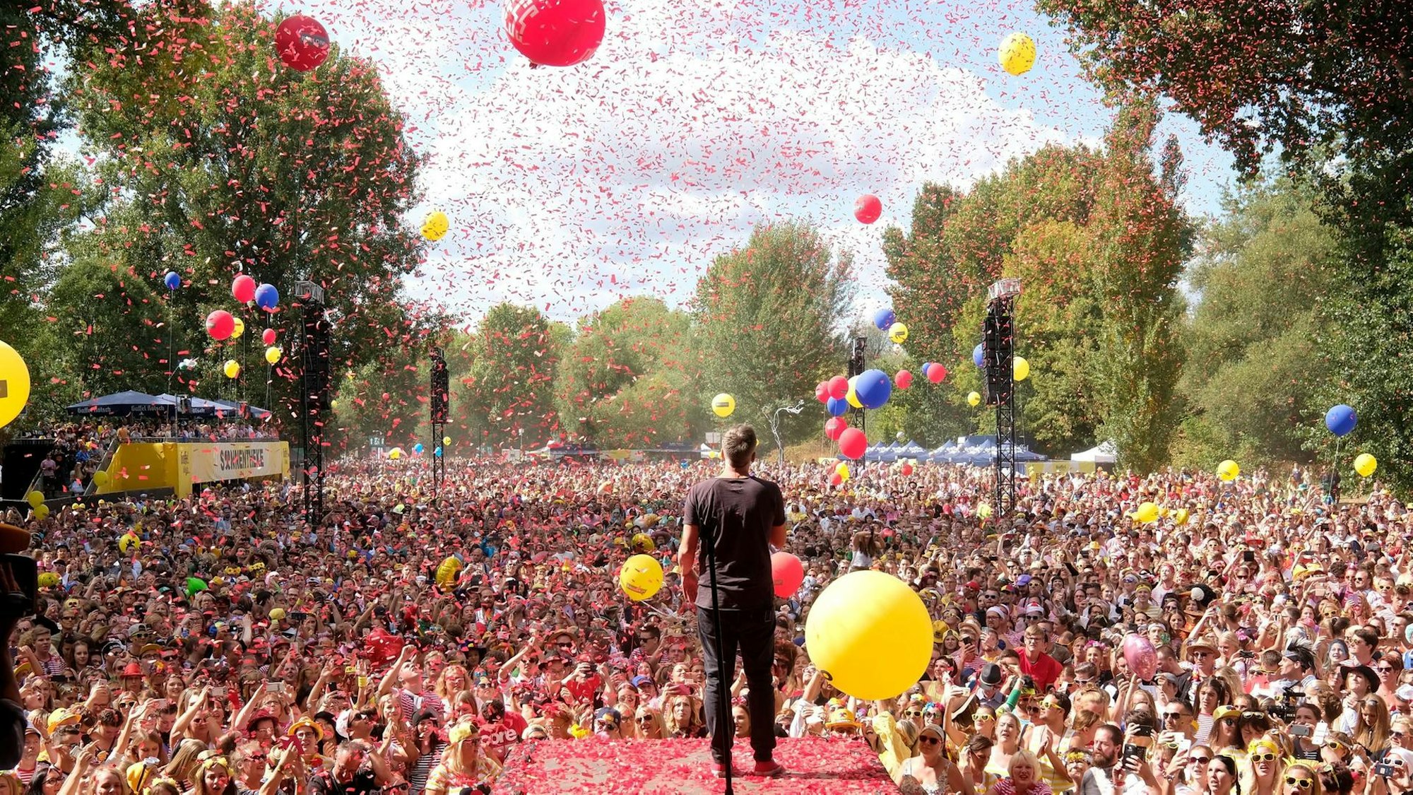 Das Publikum und die Bühne bei „Jeck im Sunnesching”. Es fliegt Konfetti und Luftballons steigen auf.