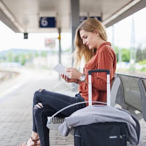 Frau am Bahnsteig mit Handy